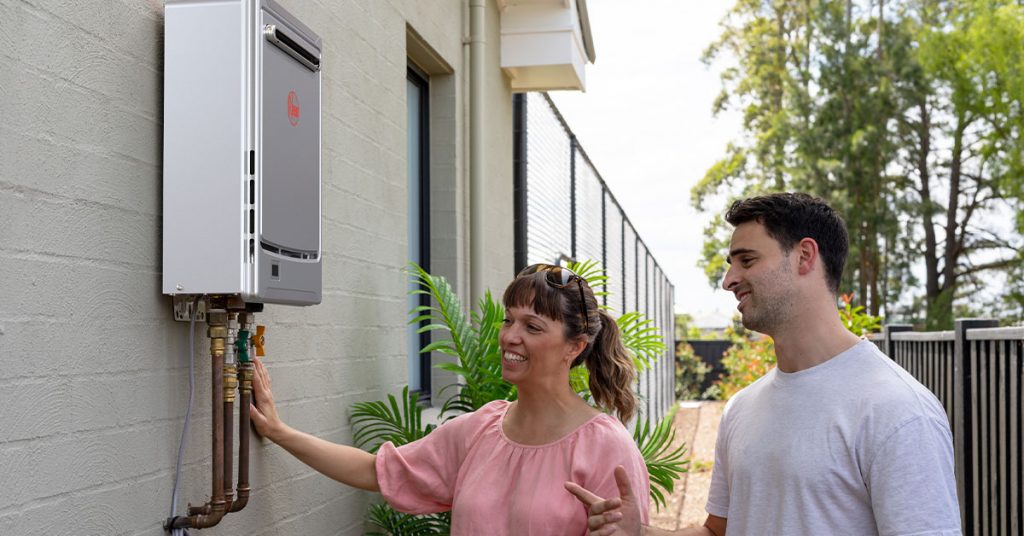 Plumber with homeowner inspecting a Rheem Gas Continuous Flow water heater.
